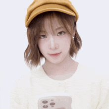 a woman wearing a yellow hat holds a white phone