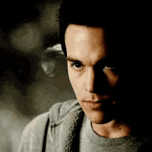 a close up of a man 's face with a gray shirt on