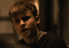 a close up of a young man 's face with a sweater on