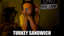 a person covering their face with a turkey sandwich sign in the background