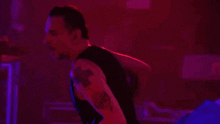 a man singing into a microphone while wearing a black tank top