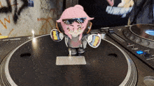 a doll with a sticker that says wow on it stands on a turntable