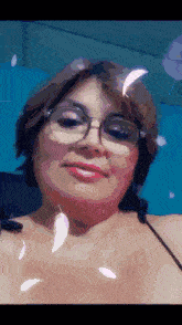a woman wearing glasses is smiling with feathers flying around her face