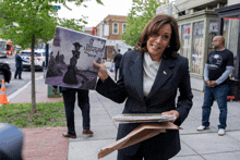 a woman in a suit is holding a picture of a woman in a dress