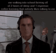 a man in a suit and tie wearing headphones is walking into school thriving off of 2 hours of sleep and 1 espresso coffee .