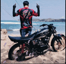 a man stands next to a motorcycle on the beach
