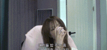 a woman is covering her face with her hands in front of a door in a room .