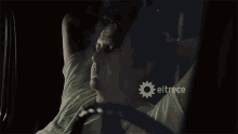 a man laying in a car with eltrece written on the bottom right
