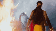 a man and a woman are standing in front of a fire