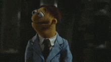 a muppet is wearing a suit and tie and making a funny face .