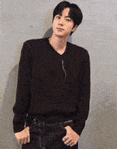 a young man wearing a black sweater and blue jeans