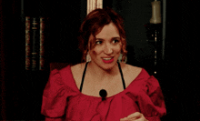 a woman in a red top with a microphone in front of her
