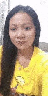 a woman is wearing a yellow shirt with a picture of spongebob on it and taking a selfie .