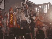 a man in a hot dog costume is standing in front of a barbecue grill