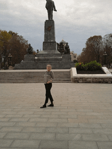 a woman stands in front of a large statue of lenin