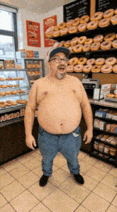 a man without a shirt is standing in front of a display of donuts in a store