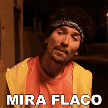 a man with a bandana on his head is wearing a yellow vest and an orange shirt with mira flaco written on the bottom