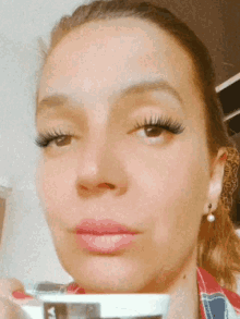 a close up of a woman 's face with a cup of coffee in her hand