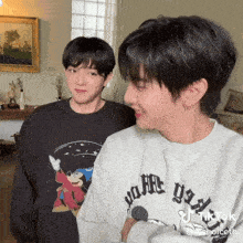 two young men are standing next to each other and one has a disney shirt on