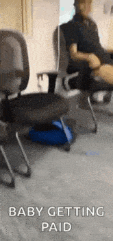 a man is sitting in an office chair with his legs crossed and a bag on the floor .