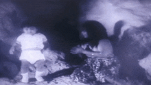 a black and white photo of a woman holding a baby