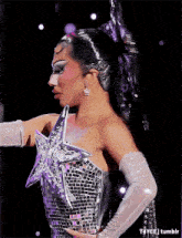 a woman is wearing a silver dress with a star on it and white gloves