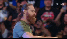 a man with a beard and long hair is standing in front of a crowd with the letters usa on the bottom right