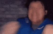a blurry picture of a man in a blue shirt making a face .