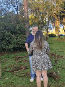 a man and a woman are standing in a park