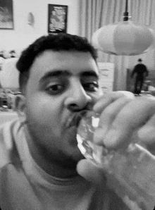 a black and white photo of a man drinking water from a glass