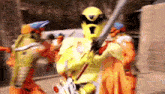 a group of people in yellow costumes are holding swords in a blurry picture .