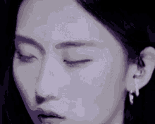 a close up of a woman 's face with her eyes closed and earring .