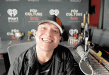 a man wearing a hat is smiling in front of a wall that says pop culture