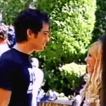 a man and a woman are standing next to each other and looking at each other in a blurry photo .