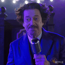 a man in a blue suit is holding a microphone with a netflix logo on the bottom