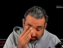 a man with a beard is covering his eyes with his hand in front of a screen that says ' ufc ' on it