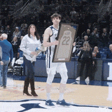 a basketball player holding a framed jersey with the number 22
