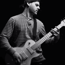 a man in a striped shirt is playing a white electric guitar