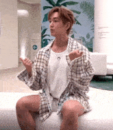 a man in a plaid shirt is sitting on a couch
