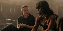 two women are sitting on the floor holding hands and talking .
