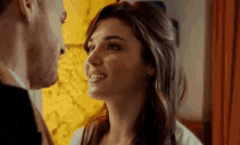 a man and a woman are kissing in front of a window .