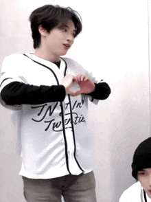 a man wearing a jersey that says tn twentie makes a heart with his hands