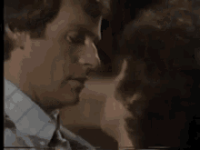 a close up of a woman kissing a man on the neck .