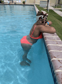 a woman in a red bikini is leaning on the edge of a swimming pool
