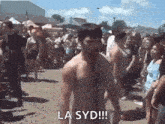 a shirtless man is standing in front of a crowd at a music festival .