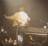 a man is singing into a microphone while a crowd watches