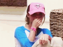 a woman wearing a pink superman hat covering her face