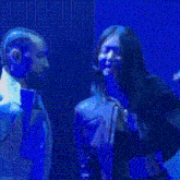 a woman with long hair is singing into a microphone on a stage in front of a blue background .