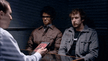 two men are sitting at a table with a man holding a book that says ' i am not a monster ' on it