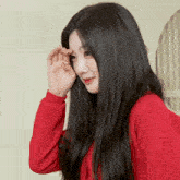 a woman with long black hair wearing a red sweater